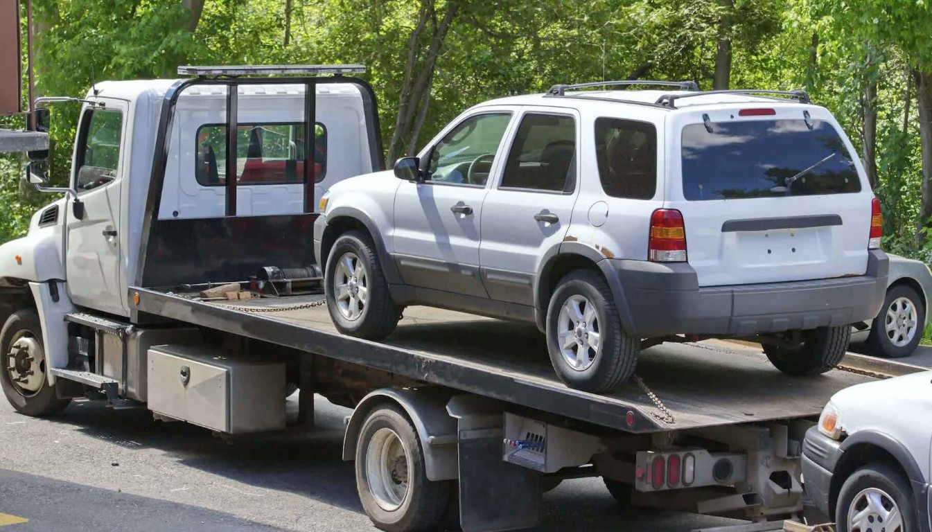 Flatbed tow truck loading a white SUV for emergency towing service in Amityville, NY