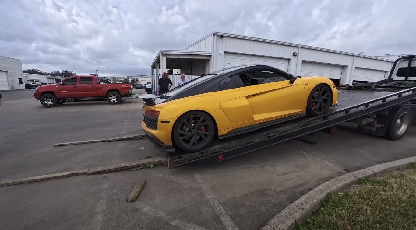 Yellow Audi sports car secured on a flatbed tow truck demonstrating safe flatbed towing methods